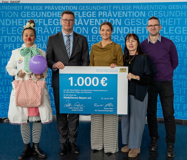 Bayerns Gesundheitsministerin Judith Gerlach (Mitte) �berreicht Elisabeth Makepeace (Vorsitzende von KlinikClowns Bayern e.V., 2. von rechts) und KlinikClown "Dr. Mathilda Pfiffikus" die Spende. Foto: StMGP